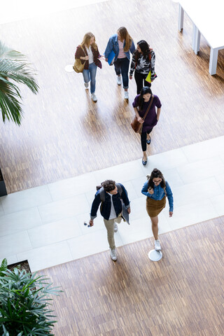 Männliche und weibliche Universitätsstudenten, die im Foyer der Universität spazieren gehen und sich unterhalten, Blickwinkel von oben, lizenzfreies Stockfoto