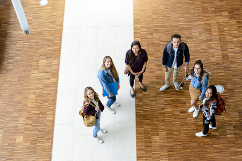 Männliche und weibliche Universitätsstudenten, die von der Universitätslobby nach oben blicken, Porträt aus hohem Winkel, lizenzfreies Stockfoto