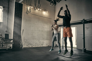 Mann und Frau im Fitnessstudio springen in der Luft - CUF44366