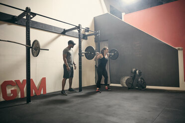 Frau im Fitnessstudio beim Gewichtheben mit der Langhantel - CUF44369