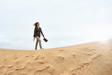 Female tourist walking barefoot on sand dune, Las Palmas, Gran Canaria, Canary Islands, Spain - CUF44422