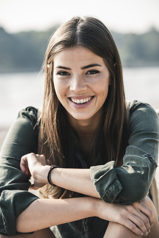 Porträt einer lächelnden jungen Frau, die im Freien sitzt, lizenzfreies Stockfoto