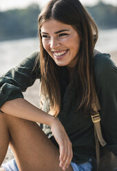 Porträt einer glücklichen jungen Frau, die im Freien sitzt - UUF15320