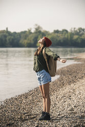 Happy young woman standing at the riverside - UUF15333