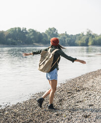 Carefree young woman walking at the riverside - UUF15335