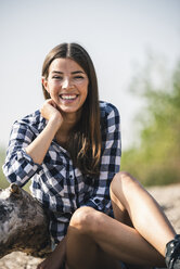 Portrait of happy young woman sitting outdoors - UUF15339