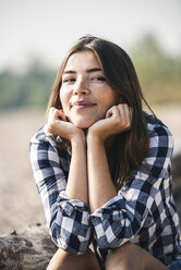 Portrait of smiling young woman sitting outdoors - UUF15344