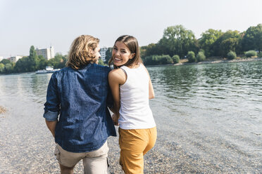 Glückliches, verliebtes junges Paar beim Spaziergang am Flussufer - UUF15376