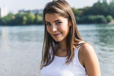 Porträt einer lächelnden jungen Frau am Flussufer - UUF15379