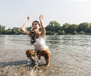 Sorglose junge Frau erfrischt sich im Wasser eines Flusses - UUF15380