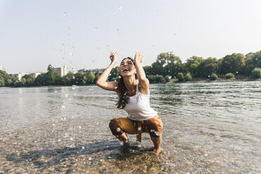 Sorglose junge Frau erfrischt sich im Wasser eines Flusses - UUF15381