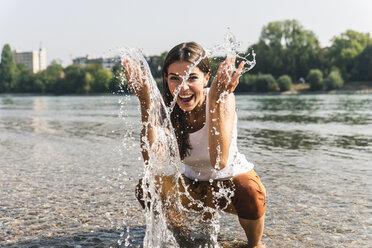 Sorglose junge Frau erfrischt sich im Wasser eines Flusses - UUF15382