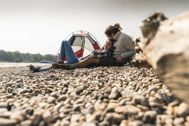Glückliches junges Paar entspannt sich in einem Zelt am Flussufer - UUF15406