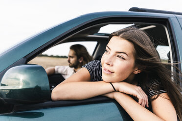 Smiling young woman leaning out of car window - UUF15415