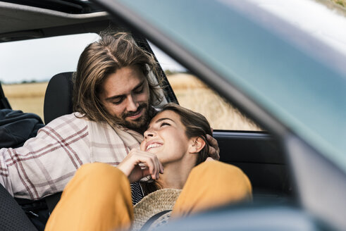 Glückliches, zärtliches junges Paar im Auto - UUF15436