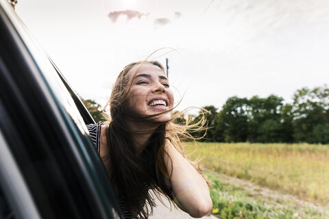 Happy young woman leaning out of car window stock photo