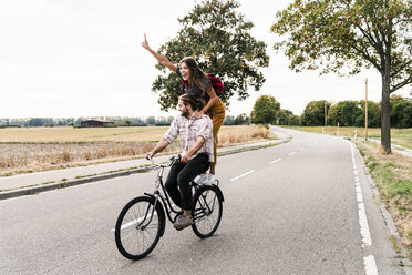 Happy young couple riding together on one bicycle on country road - UUF15446