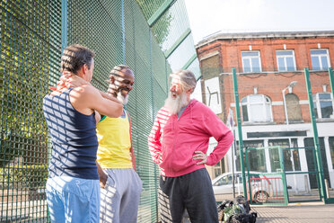 Drei reife Männer auf dem Basketballplatz, die zusammen lachen - CUF44458