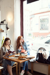 Frauen, die in einem Café lesen und mit dem Handy telefonieren - CUF44529