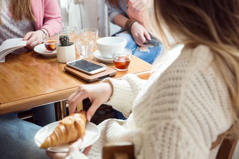 Frauen plaudern bei Kaffee und Croissant im Cafe, lizenzfreies Stockfoto