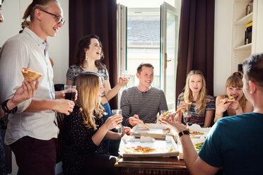 Eine Gruppe von Freunden unterhält sich bei Getränken und Pizza zu Hause - CUF44541