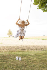 Happy mature woman on swing in remote countryside - JUNF01442