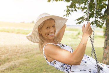 Happy mature woman on swing in remote countryside - JUNF01443