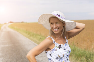 Lächelnde reife Frau auf abgelegenem Feldweg im Sommer - JUNF01449