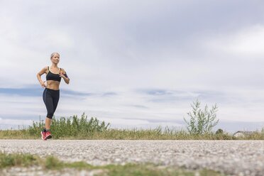 Ältere Frau läuft auf abgelegenem Feldweg im Sommer - JUNF01455