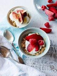 Still life of nut muesli and yogurt in bowls with fresh fruit, overhead view - CUF44606