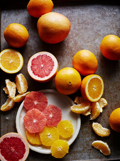 Stilleben mit Orangen und Grapefruits, ganz, halbiert und in Scheiben geschnitten, Draufsicht - CUF44641
