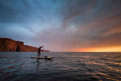 Paddelboarder auf dem Wasser bei Sonnenuntergang, Cliffs of Moher, Doolin, Clare, Irland - CUF44864