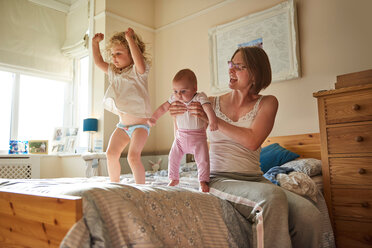 Frau auf dem Bett spielt mit Baby und Kleinkind Töchter - CUF44907