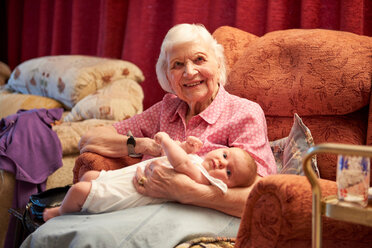 Senior woman cradling baby great granddaughter on armchair, portrait - CUF44911