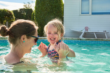Woman holding toddler daughter hands in swimming pool - CUF44915