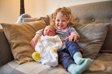 Weibliches Kleinkind und kleine Schwester auf dem Sofa, Porträt - CUF44918