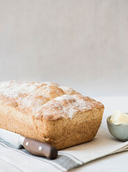 Freshly baked loaf of whole wheat bread with knife and butter - CUF44923