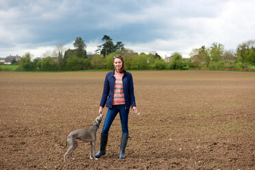 Mittlere erwachsene Frau und Whippet-Hund im Feld, Porträt - CUF44955