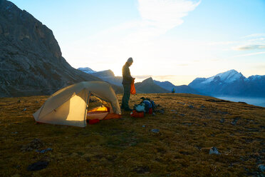 Hiker by tent at sunset, Canazei, Trentino-Alto Adige, Italy - CUF44973