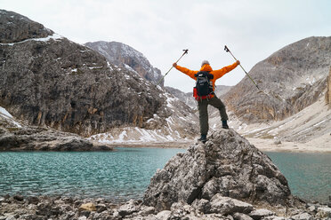 Hiker admiring view by lake, Canazei, Trentino-Alto Adige, Italy - CUF44977