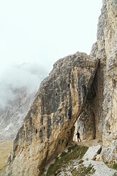 Hiker passing under stone arch, Canazei, Trentino-Alto Adige, Italy - CUF44986