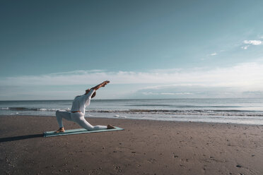 Woman practising yoga on beach - CUF44990