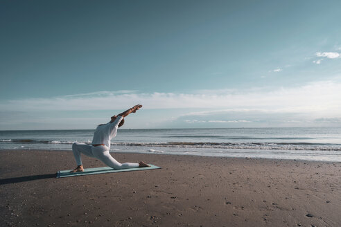 Woman practising yoga on beach - CUF44990