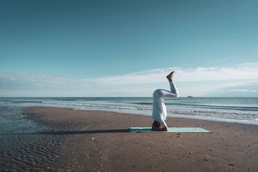 Woman practising yoga on beach - CUF44991