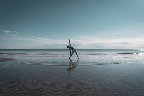 Woman practising yoga on beach - CUF44996