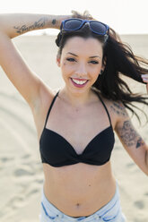 Portrait of tattooed young woman with nose piercing and tattoo on the beach - GIOF04622