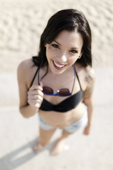 Porträt einer lächelnden jungen Frau mit Nasenpiercing am Strand - GIOF04638