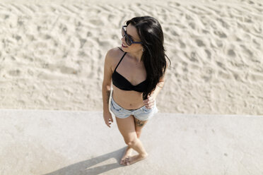 Lächelnde junge Frau, die in der Nähe des Strandes steht, Blick von oben - GIOF04640