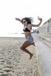 Portrait of happy young woman jumping on the beach - GIOF04641