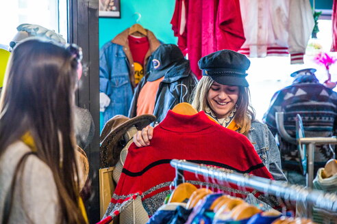 Friends browsing vintage clothes in thrift store - CUF45085